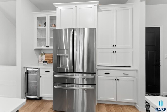 kitchen featuring white cabinetry, stainless steel refrigerator with ice dispenser, beverage cooler, and light hardwood / wood-style floors