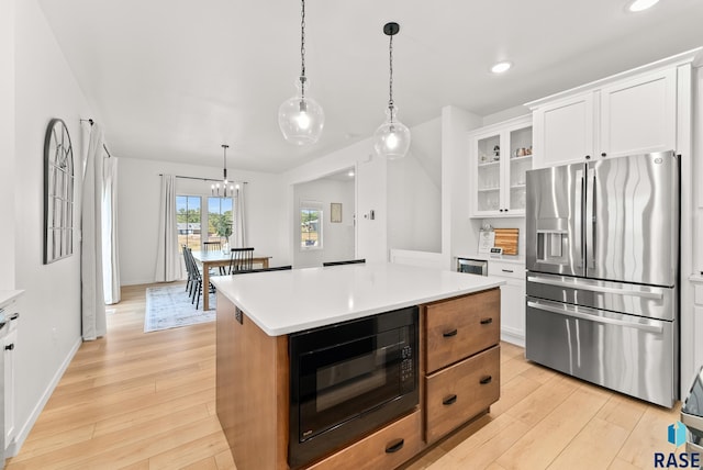 kitchen with light hardwood / wood-style flooring, stainless steel fridge, black microwave, a center island, and white cabinets