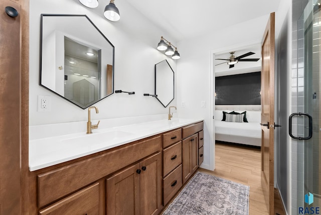 bathroom featuring walk in shower, ceiling fan, wood-type flooring, and vanity