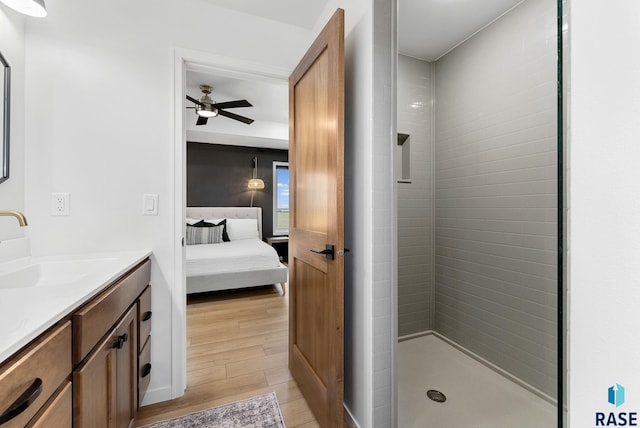 bathroom featuring vanity, ceiling fan, hardwood / wood-style flooring, and tiled shower