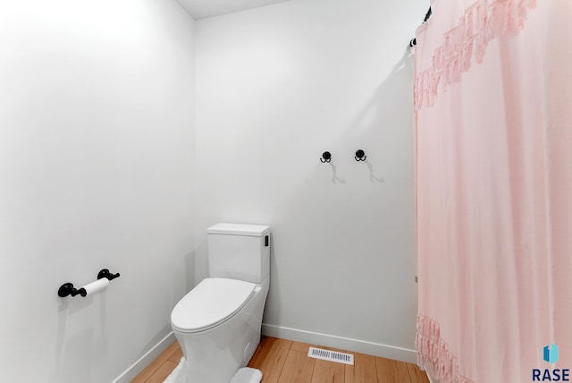 bathroom featuring wood-type flooring and toilet