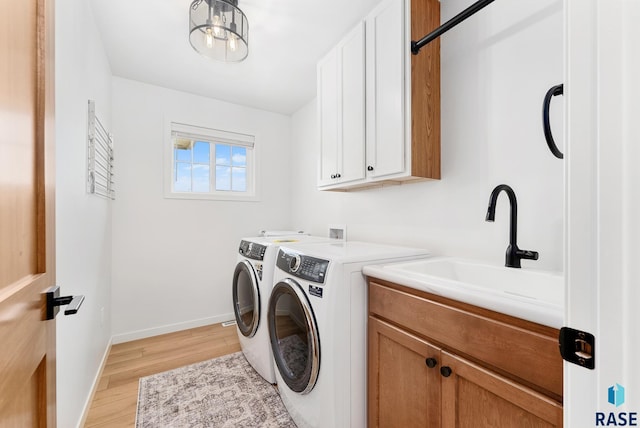 washroom with cabinets, light wood-type flooring, sink, and independent washer and dryer