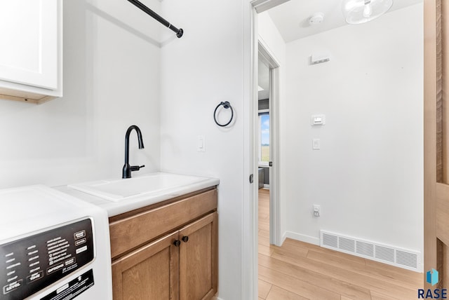 interior space with white cabinetry, sink, washer and clothes dryer, and light wood-type flooring