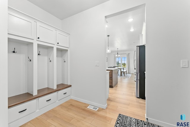 mudroom featuring a notable chandelier and light wood-type flooring