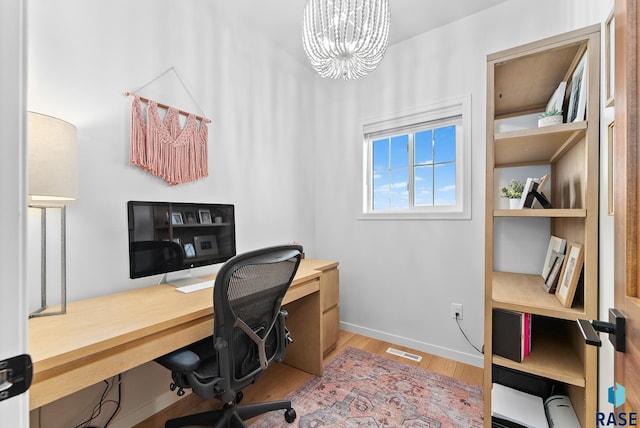 home office with an inviting chandelier and light hardwood / wood-style floors