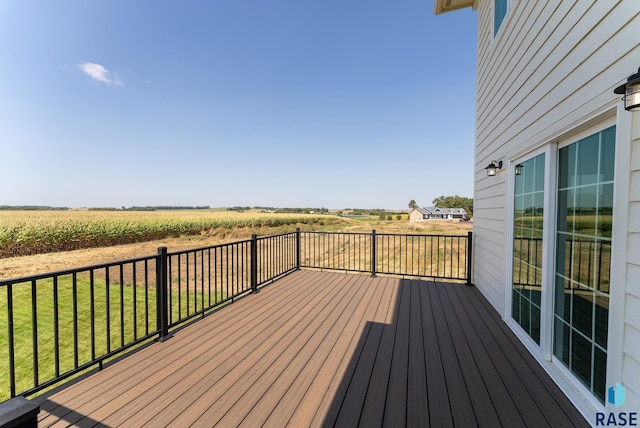 wooden terrace with a rural view and a lawn