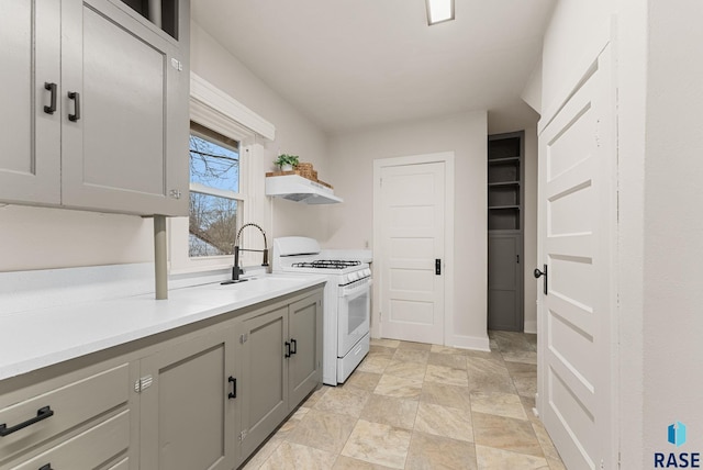 kitchen with gray cabinets, white gas range, and sink