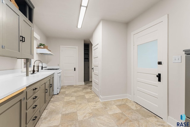 kitchen featuring sink, white gas stove, and gray cabinetry