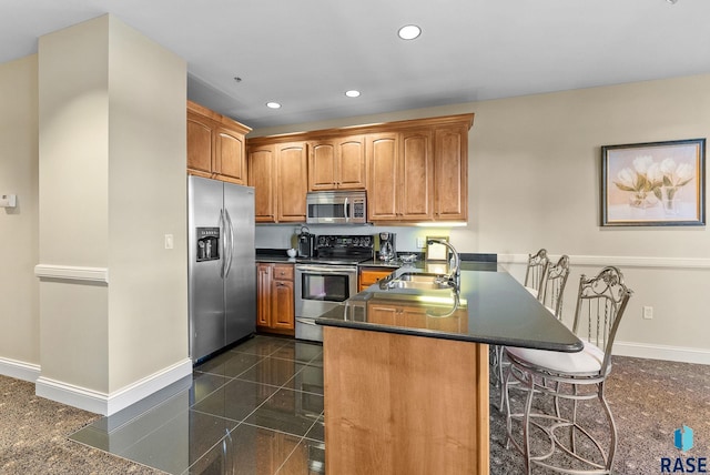 kitchen featuring appliances with stainless steel finishes, sink, a kitchen bar, and kitchen peninsula