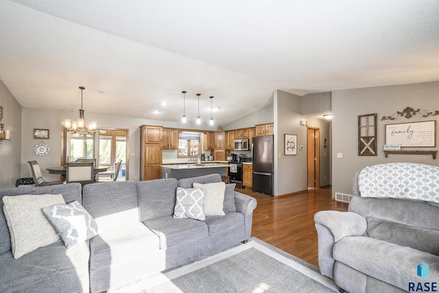 living room with lofted ceiling, hardwood / wood-style floors, and a notable chandelier