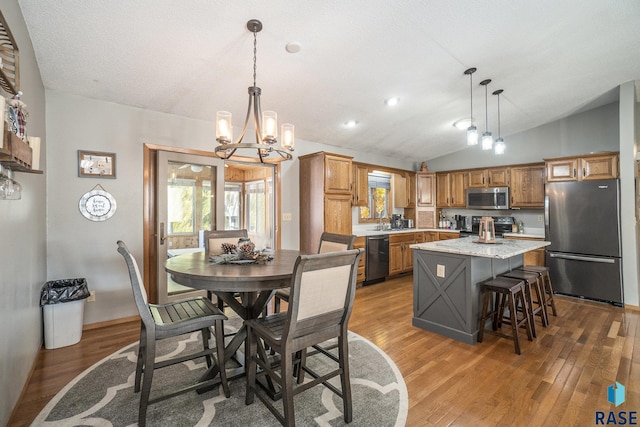 dining room with lofted ceiling, hardwood / wood-style floors, a notable chandelier, and a textured ceiling