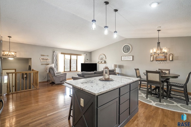 kitchen featuring a center island, light stone countertops, hanging light fixtures, and a notable chandelier