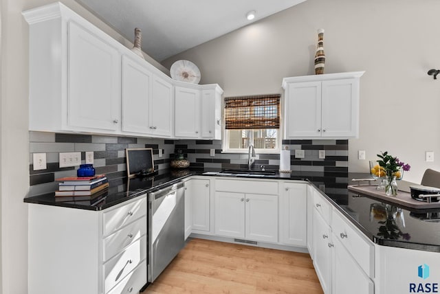 kitchen with vaulted ceiling, white cabinetry, sink, decorative backsplash, and stainless steel dishwasher