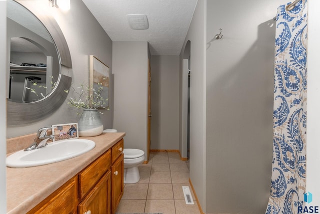 bathroom featuring tile patterned flooring, vanity, toilet, and a textured ceiling