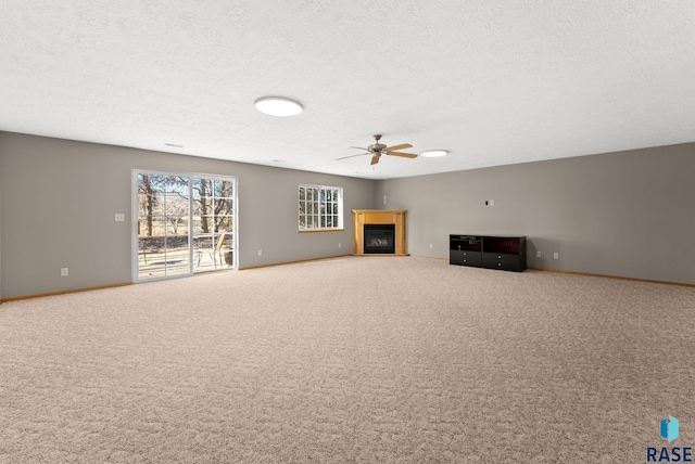 unfurnished living room with ceiling fan, carpet floors, and a textured ceiling