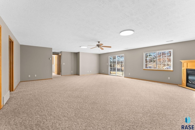 unfurnished living room featuring a textured ceiling, light colored carpet, and ceiling fan