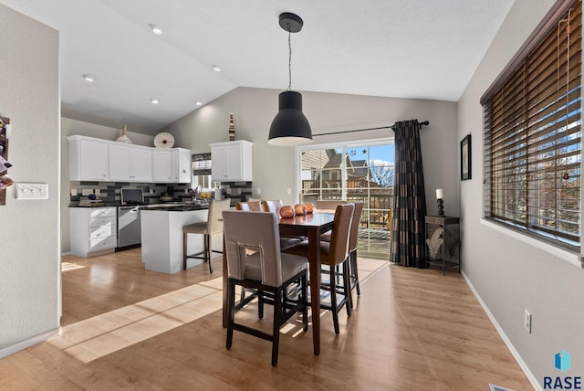 dining room with vaulted ceiling and light hardwood / wood-style floors