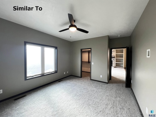 unfurnished bedroom with a spacious closet, light carpet, and ceiling fan