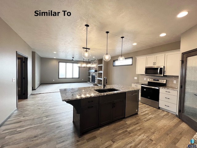 kitchen featuring sink, white cabinetry, wood-type flooring, appliances with stainless steel finishes, and a kitchen island with sink