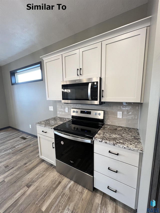 kitchen with stainless steel appliances, stone countertops, light wood-type flooring, and white cabinets