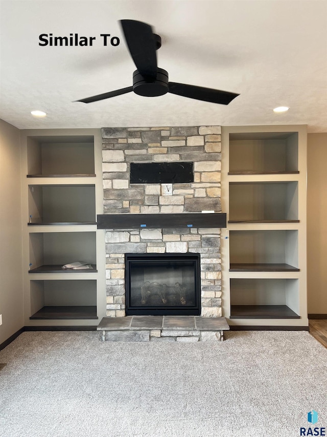 unfurnished living room featuring a stone fireplace, built in features, light colored carpet, and ceiling fan