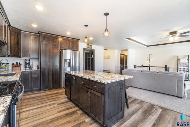 kitchen with light stone counters, dark brown cabinetry, stainless steel appliances, and a kitchen island