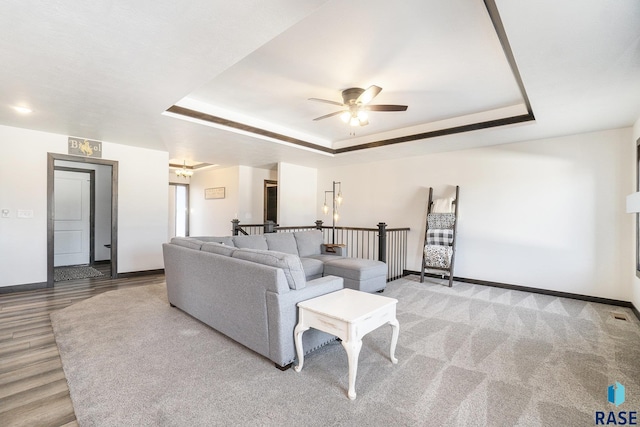 living room with ceiling fan and a raised ceiling