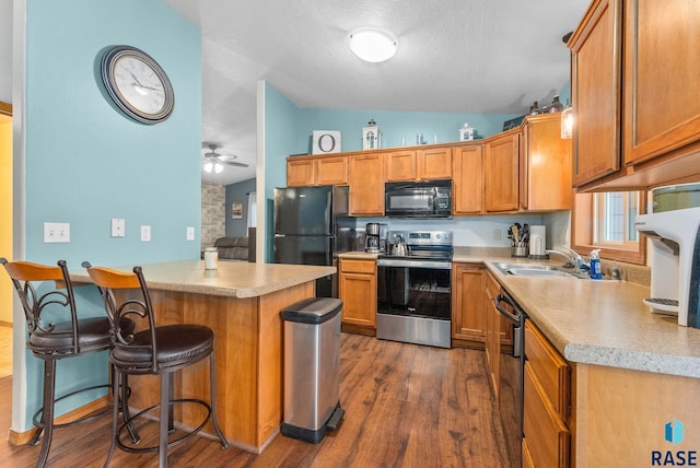 kitchen featuring sink, dark hardwood / wood-style floors, black appliances, a kitchen bar, and vaulted ceiling