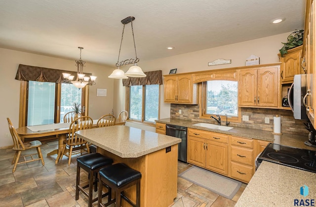 kitchen featuring sink, dishwasher, a center island, tasteful backsplash, and decorative light fixtures