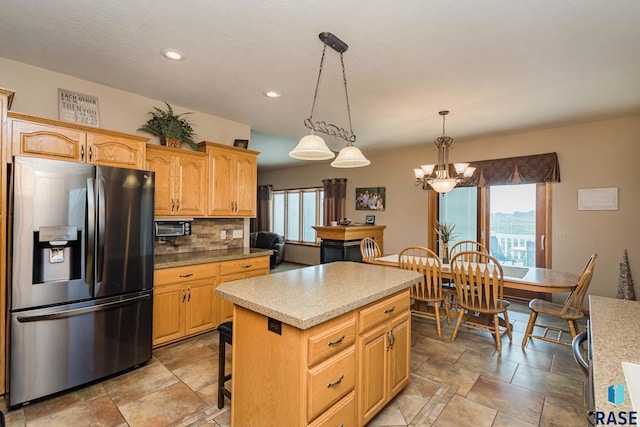 kitchen featuring pendant lighting, stainless steel fridge, a breakfast bar area, a center island, and tasteful backsplash