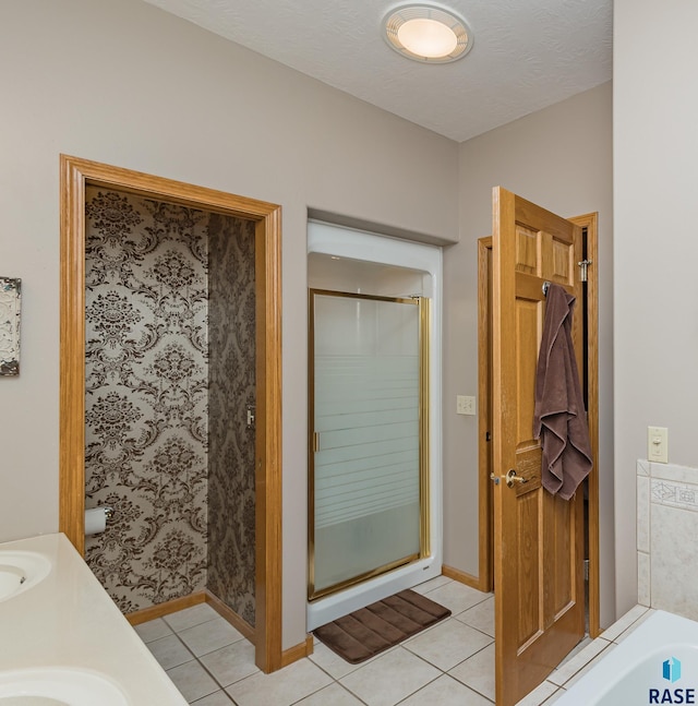 bathroom with tile patterned flooring, vanity, a textured ceiling, and walk in shower