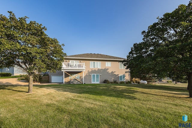 rear view of house with a garage, a yard, and a deck