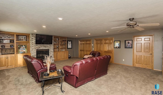 carpeted living room featuring ceiling fan, a textured ceiling, and a fireplace