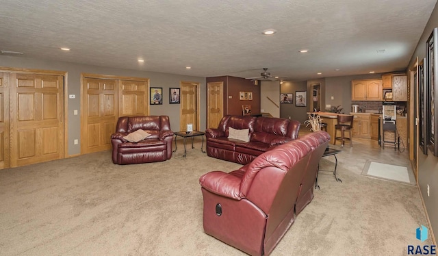 living room featuring light carpet, ceiling fan, and a textured ceiling