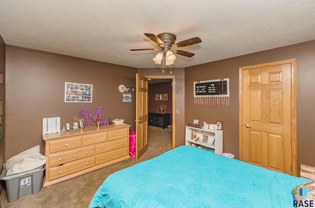 bedroom with ceiling fan, dark carpet, and a textured ceiling