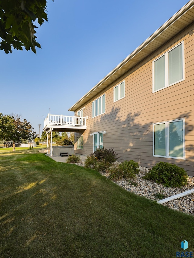 rear view of house with a yard, a hot tub, and a deck