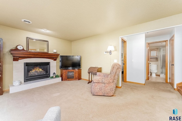 living room featuring a tiled fireplace, carpet floors, and a textured ceiling