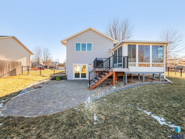 rear view of house with a wooden deck, a sunroom, a yard, and a patio area