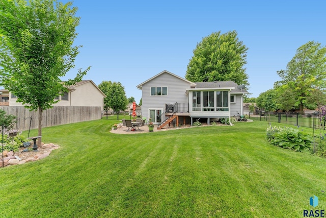 back of property with a wooden deck, a patio, a sunroom, and a lawn