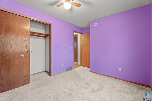 unfurnished bedroom with ceiling fan, light colored carpet, a closet, and a textured ceiling