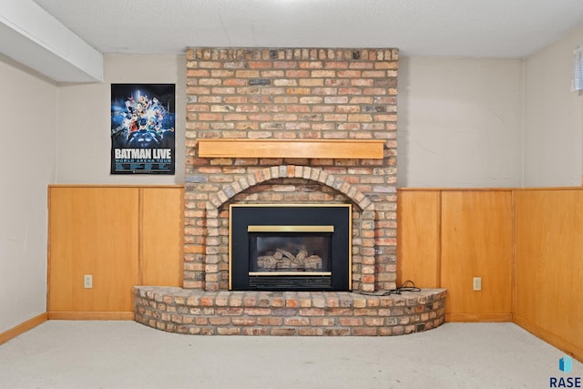 carpeted living room featuring a fireplace, a textured ceiling, and wood walls