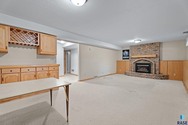 unfurnished living room with wooden walls, a fireplace, light colored carpet, and a textured ceiling