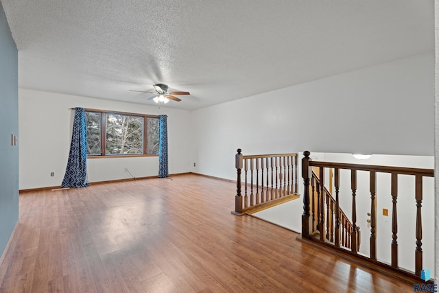 empty room with ceiling fan, hardwood / wood-style floors, and a textured ceiling