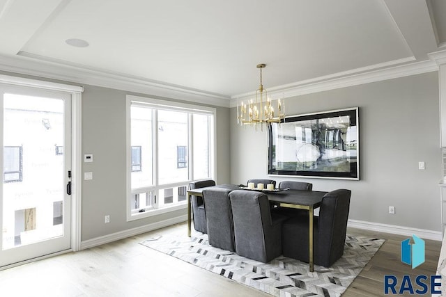 dining area featuring a raised ceiling, crown molding, wood-type flooring, and a notable chandelier