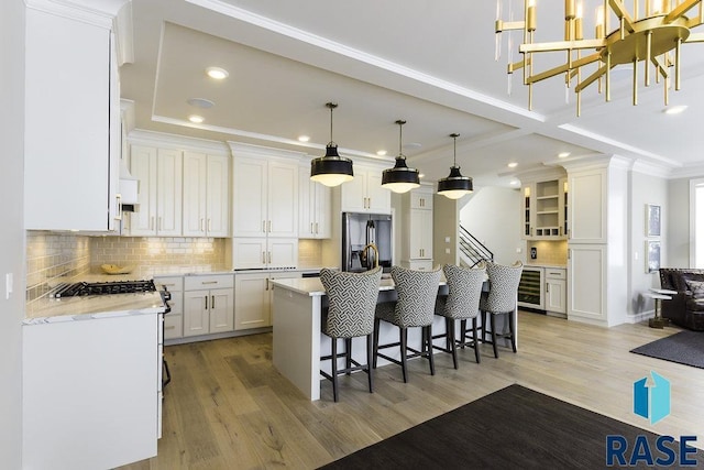 kitchen featuring stainless steel fridge with ice dispenser, hanging light fixtures, a kitchen island, beverage cooler, and white cabinets