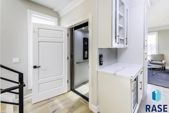 laundry room with ornamental molding and light hardwood / wood-style flooring