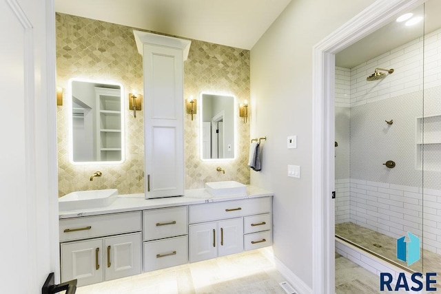 bathroom with tiled shower, vanity, and decorative columns