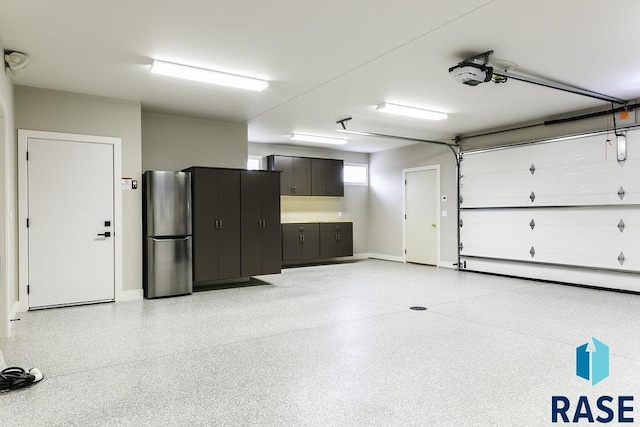 garage featuring baseboard heating, a garage door opener, and stainless steel fridge