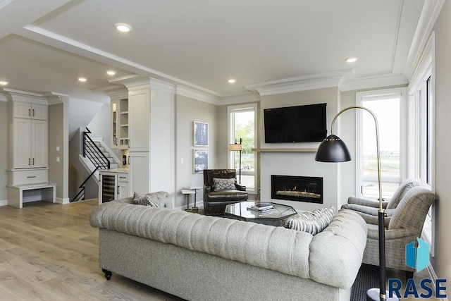 living room with crown molding, beverage cooler, and light wood-type flooring