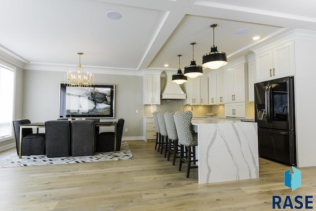 kitchen featuring fridge with ice dispenser, light stone counters, white cabinetry, and decorative light fixtures